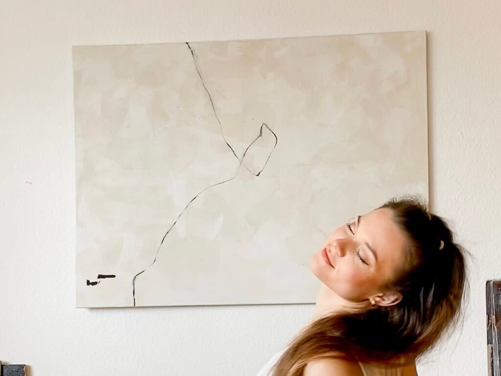 Artist Lorena Krüner sitting in a chair in front of her Artwork