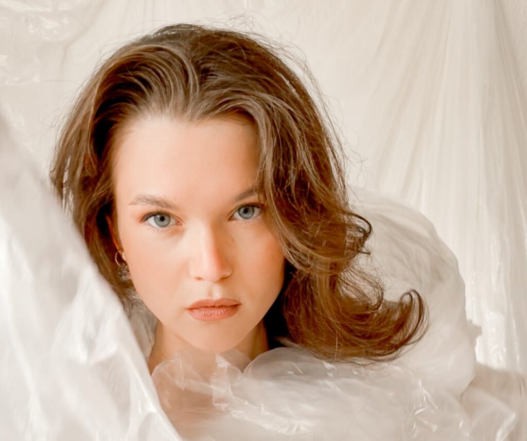 A portrait of a female visual artist Lorena Krüner wrapped in a plastic foil in a creative photoshoot of her.